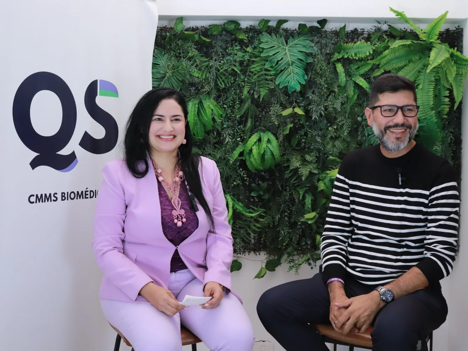 Dos profesionales conversan en un espacio de QS con un muro vegetal.