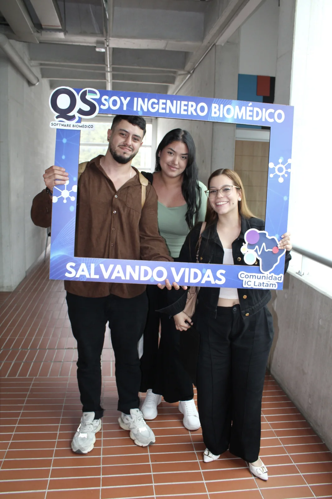 Tres integrantes de la comunidad posan con un marco de reconocimiento a la ingeniería biomédica.